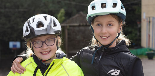 Two girls wearing cycling helmets to illustrate extra-curricular activities